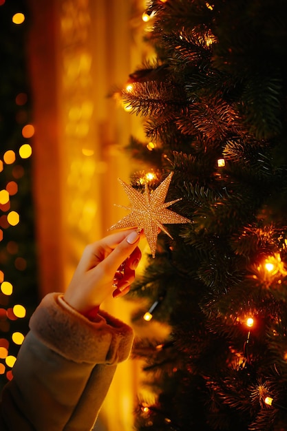 Kobieca ręka z bożonarodzeniowymi lampkami na drzewie Świąteczny jarmark bożonarodzeniowy koncepcja ferii zimowych
