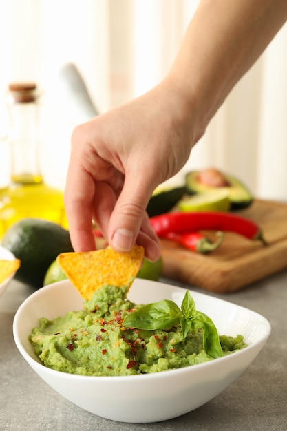 Kobieca Ręka Zanurza Kawałek Chipsów W Guacamole