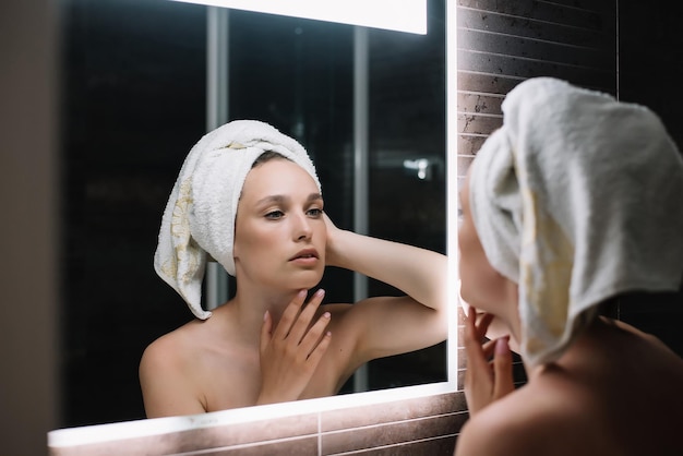 Kobieca twarz odbita w lustrzanym poziomym banerze po prysznicu z ręcznikiem na głowie Kobieta w wieku 30 lat