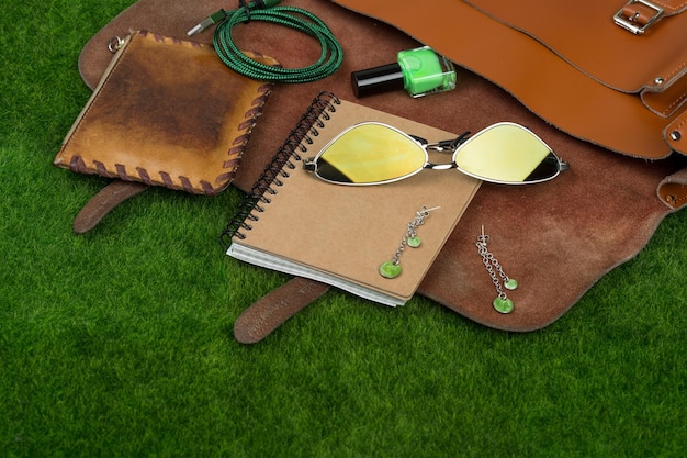 Kobiece akcesoria modowe torba notatnik torebka niezbędne lakiery do paznokci na trawie