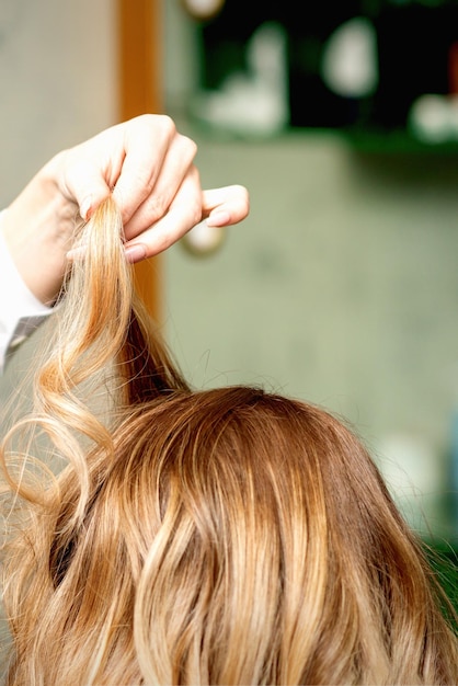 Kobiece coiffeur ustalające fryzurę blond kobieta z lakierem do włosów w salonie piękności.