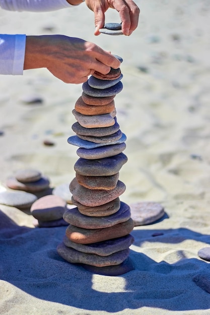 Kobiece Dłonie Budują Piramidę Z Kamieni Na Piaszczystej Plaży