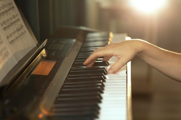 kobiece dłonie dotykają klawiszy fortepianu grają melodię w promieniach zachodzącego słońca