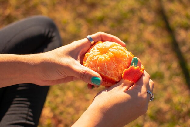 Kobiece dłonie obierające mandarynki