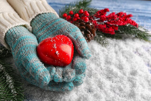 Kobiece dłonie w rękawiczkach z ozdobnym sercem na tle śniegu