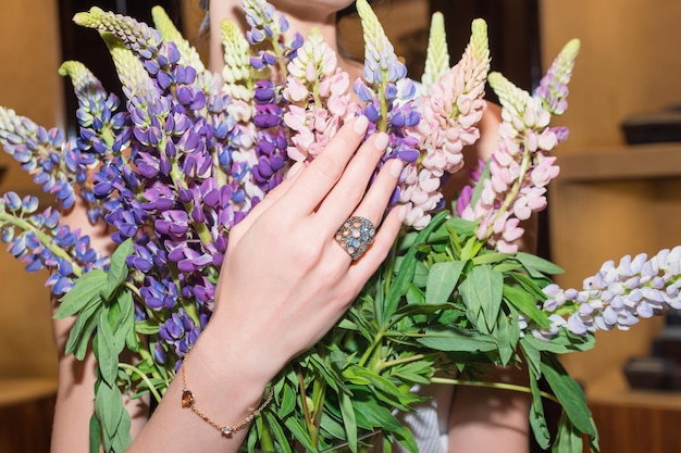 Kobiece dłonie z manicure i luksusową biżuterią pierścionki zbliżenie kobiecej dłoni na kwiatach pokazujących modę...