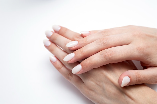 Kobiece dłonie z profesjonalnym manicure w beżowych kolorach.