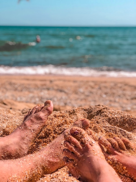 Kobiece i męskie stopy na zbliżenie piaszczystej plaży muszla na tle lazurowej wody morskiej. Koncepcja wakacji i podróży.