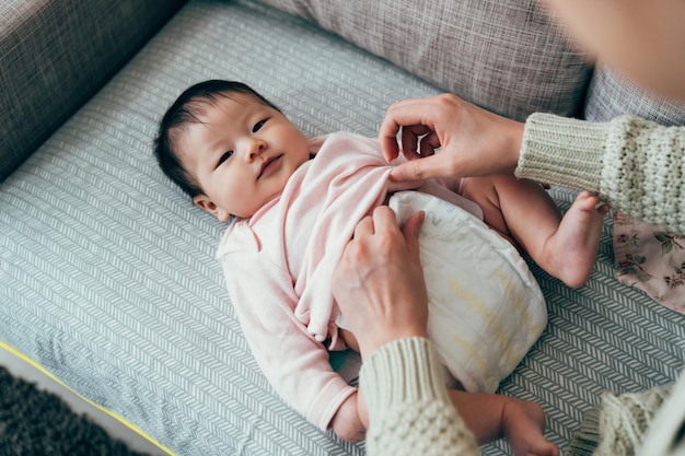 kobiece niemowlę uczucie suche i wygodne uśmiecha się do kamery. przycięty widok dozorca zakłada czystą pieluchę dla uroczego dziecka.