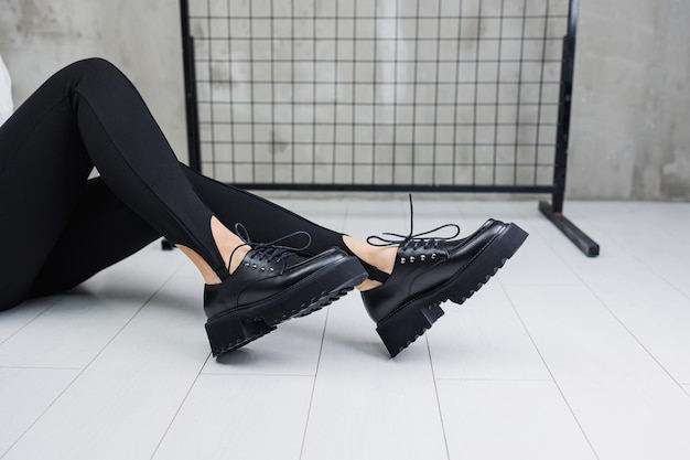 Kobiece nogi w modnych czarnych legginsach i mokasynach na skórzanych butach szczegóły stylowego jesiennego wyglądu