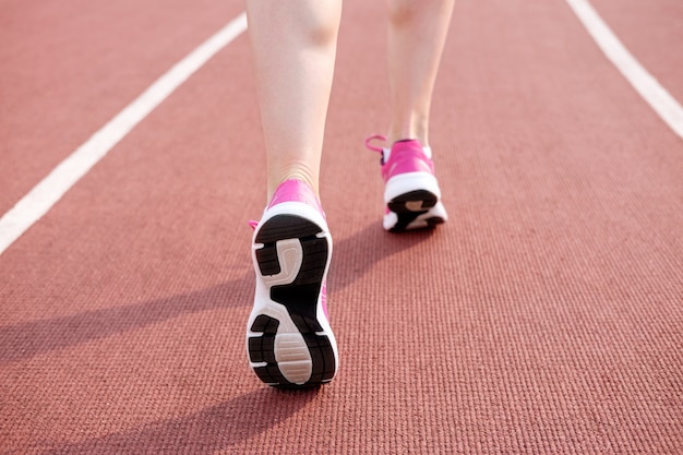 Kobiece nogi w różowe trampki na stadionie bieżni