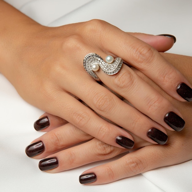 Kobiece paznokcie z pierścionkiem na środkowym palcu.