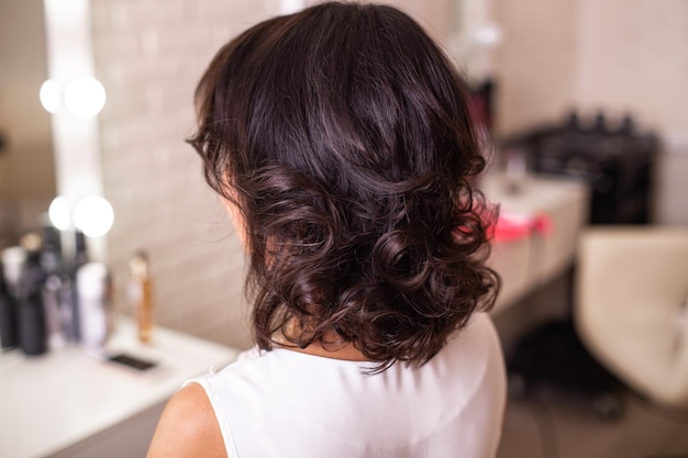 Kobiece plecy z krótkimi kręconymi włosami w salonie fryzjerskim