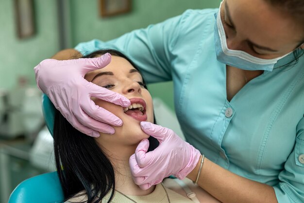 Kobiece ręce dentysty bada usta pacjenta, klinika stomatologiczna