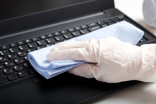 Zdjęcie kobiece ręce dezynfekcji klawiatury laptopa za pomocą wilgotnych chusteczek dezynfekujących. nowe normalne powierzchnie czyszczące