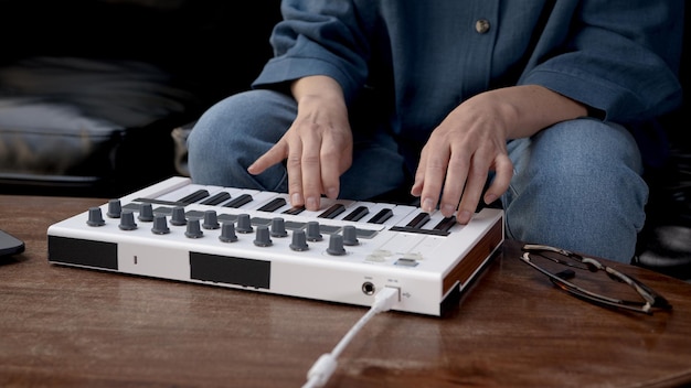 Zdjęcie kobiece ręce grające na małej klawiaturze producent muzyki zbliżenie dłoni grających na klawiszach domowe studio nagrań z profesjonalnym sprzętem