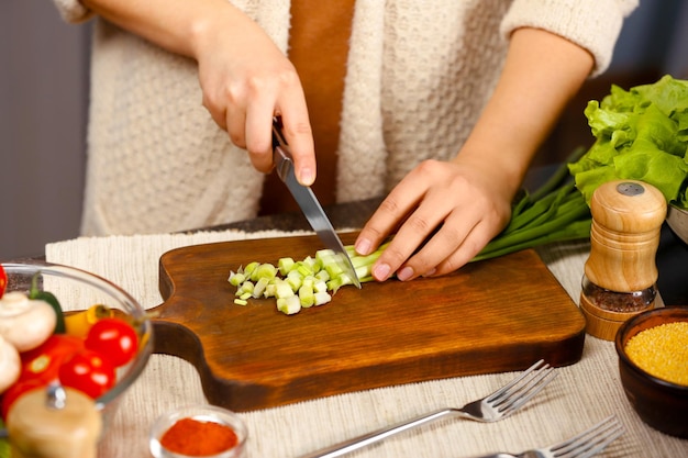 Kobiece ręce kroją warzywa przy stole w kuchni