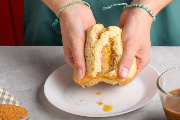 Zdjęcie kobiece ręce łamią kanapkę z miodem i masłem orzechowym z chleba pszenicznego na śniadanie