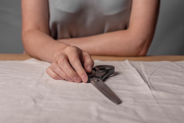 Kobiece ręce leżące metalowe nożyczki nad naturalną tkaniną koncepcja szycia domu jako modne hobby