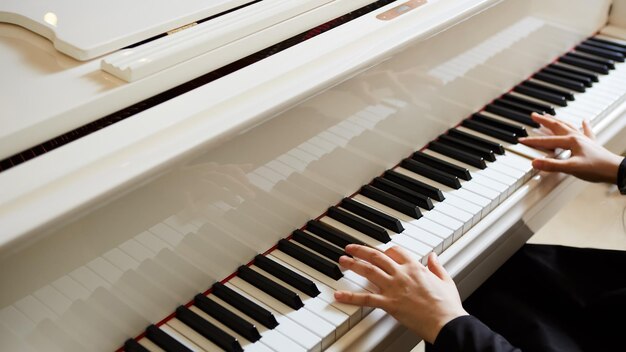 Kobiece ręce na klawiaturze fortepianu z bliska