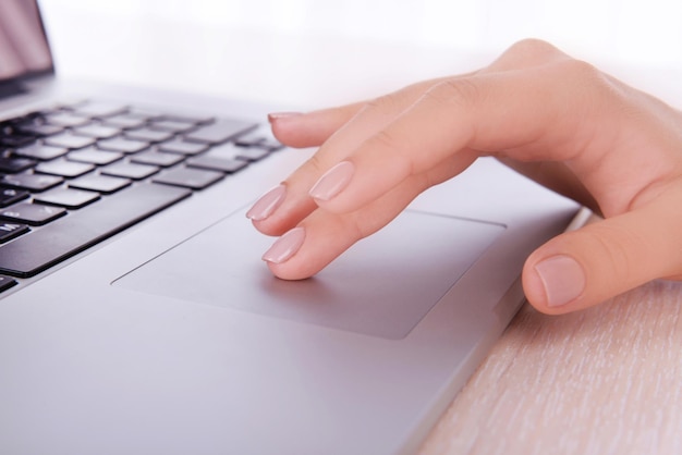 Kobiece ręce pracujące na laptopie na jasnym tle