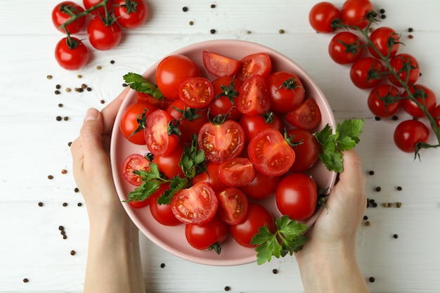 Kobiece ręce trzymać talerz z pomidorami cherry na podłoże drewniane