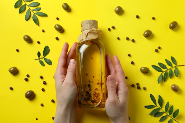 Kobiece ręce trzymają butelkę oliwy z oliwek na żółto