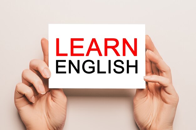 Kobiece Ręce Trzymają Kartkę Z Tekstem Learn English Na żółtej ścianie