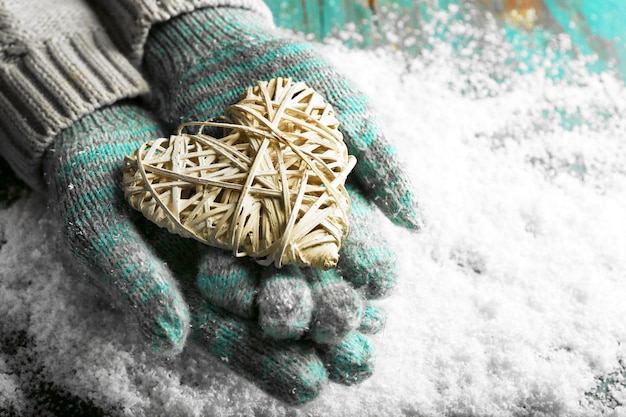 Kobiece ręce w rękawiczkach z sercem na tle śniegu