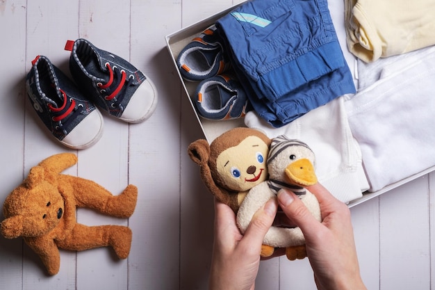 Zdjęcie kobiece ręce wkładają zabawki dla dzieci, ubrania, buty do pudełka na darowizny koncepcja recyklingu odzieży używanej