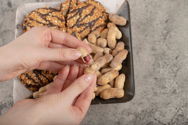 Kobiece Ręce Zbierając Organiczne Jądra Orzechów Ziemnych Na Powierzchni Kamienia.