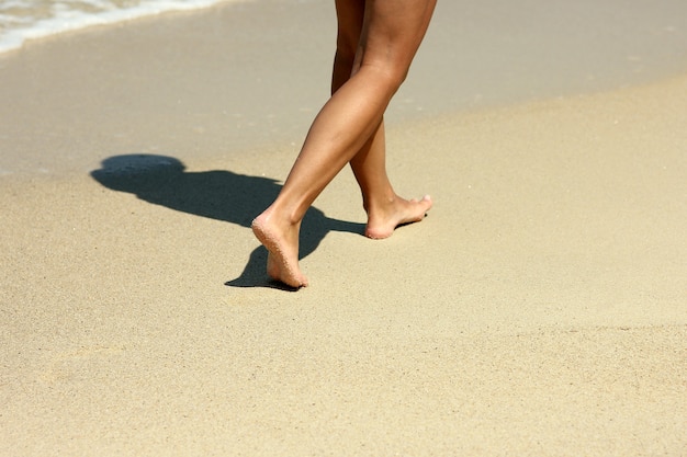 Kobiece ślady stóp na piasku na plaży latem