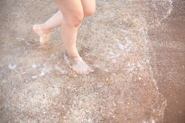 Kobiece stopy na piasku. odpoczynek i morskie powietrze.