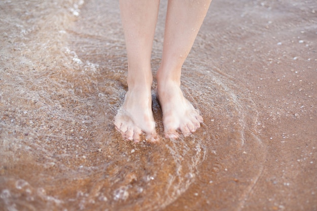 Kobiece stopy na piasku. odpoczynek i morskie powietrze.