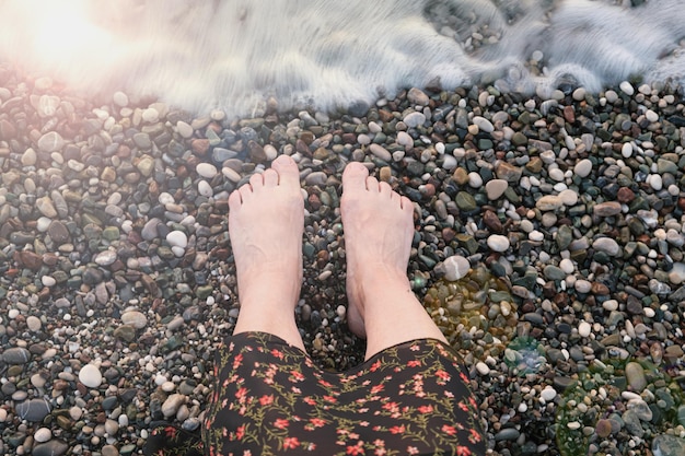 Kobiece Stopy Nad Wodą Na Kamienistej Plaży