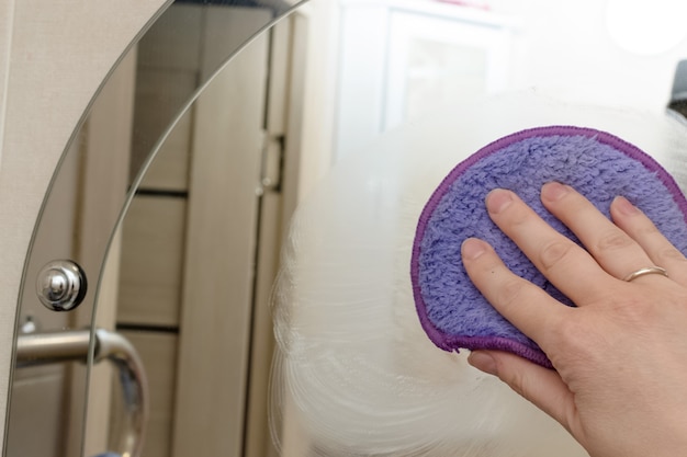 Kobiecej ręki do czyszczenia szkła z sponge.cleaning swojej łazienki.