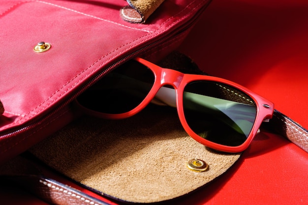 Kobieta akcesoria zbliżenie czerwone plastikowe okulary przeciwsłoneczne na czerwonym tle