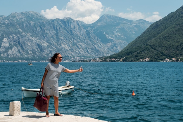Zdjęcie kobieta autostopem na molo. na molo na łódkę czeka dziewczyna.