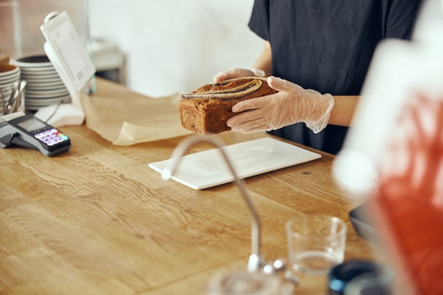 Kobieta barista w gablocie z deserami w kawiarni. Młody pracownik cukierni i kawiarni.