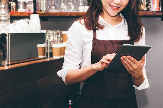 Kobieta Barista za pomocą cyfrowego tabletu obliczyć w barze licznik kawiarni