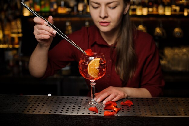 Kobieta barman dekorowanie szklanki koktajlu strzykawki Aperol z płatków róży