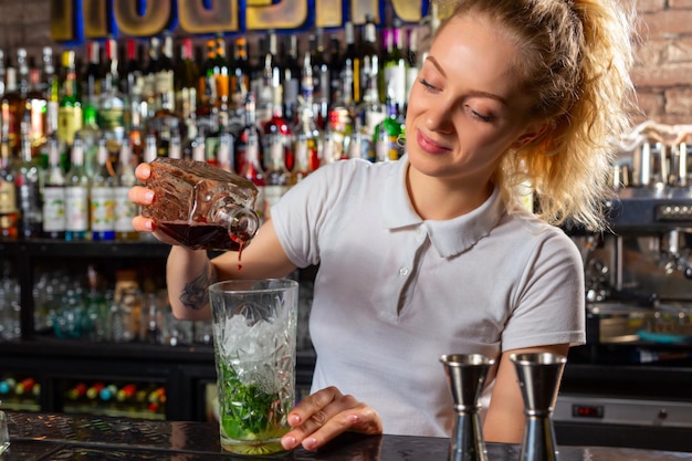 Kobieta barman robi koktajl alkoholowy