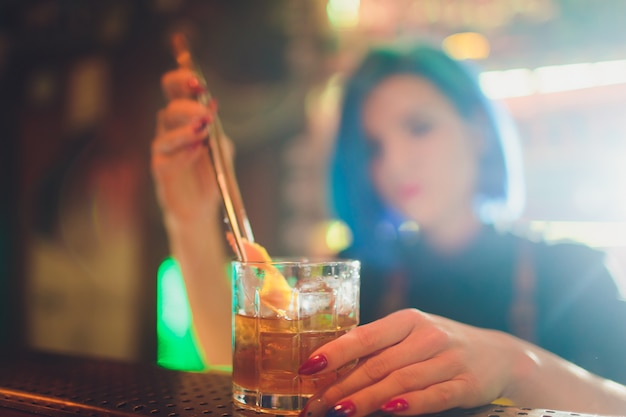 Kobieta barman rozpyla świeży pyszny koktajl za podanie go na blacie stalowej.