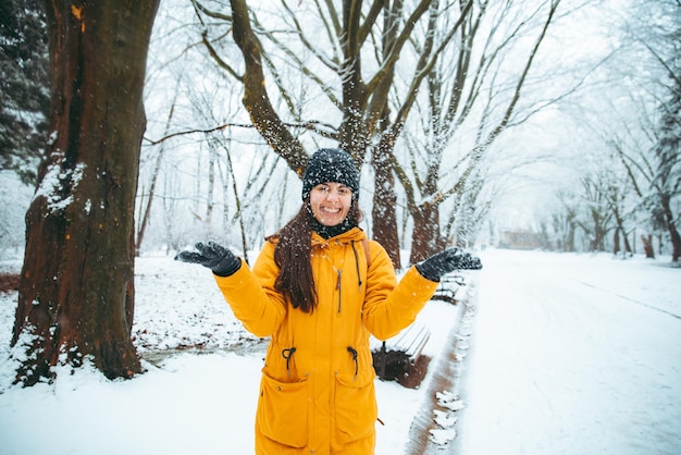 Kobieta bawi się śniegiem w zaśnieżonym parku miejskim