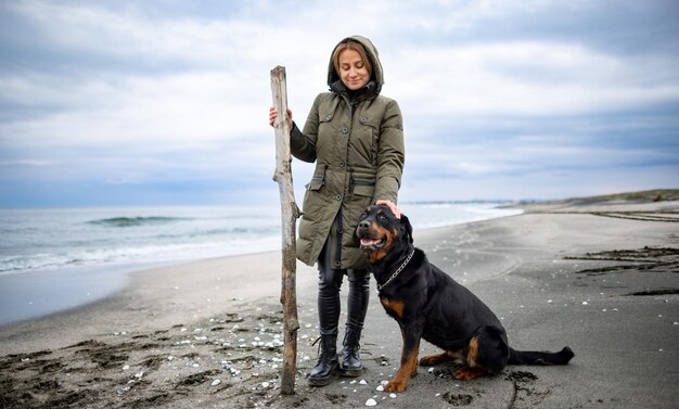 Kobieta Bawi Się Z Psem Rottweilera W Chłodne Dni Na Plaży