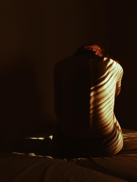 Kobieta bez koszuli siedząca w ciemni w nocy