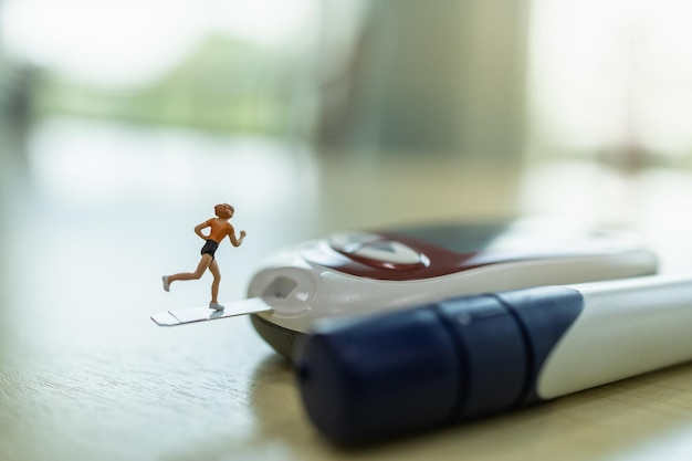 Zdjęcie kobieta biegacz miniaturowa figura działa na glukometrze z lancetem na drewnianym stole