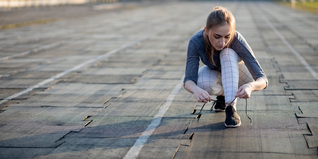 Kobieta biegacz sznurowanie jej trampki na bieżni stadionu.