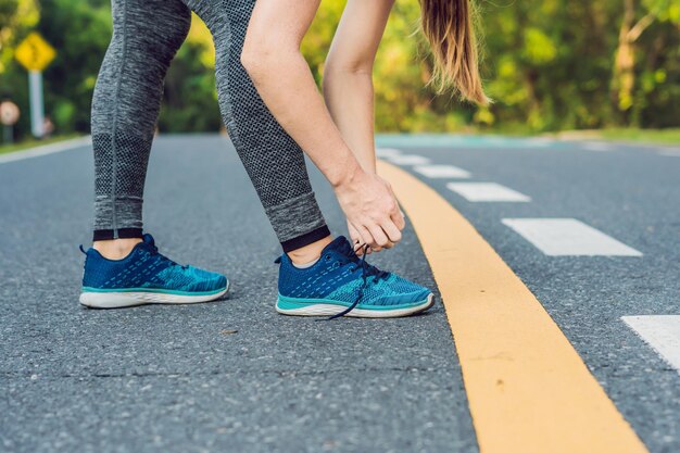 Kobieta biegacz wiązanie jej buty przygotowujące do biegania na zewnątrz. Młoda dziewczyna biegacz przygotowuje się do treningu. Sportowy styl życia