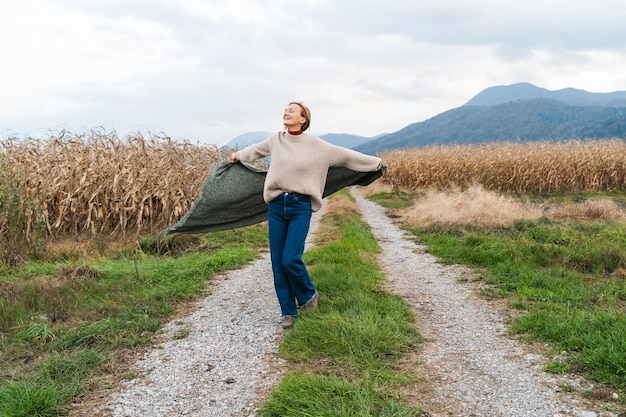 Kobieta biegająca wzdłuż drogi wśród pól uprawnych, czująca wolność i szczęście Szczęśliwa kobieta wśród pól kukurydzy jesienią Koncepcja ekologii, zrównoważonego stylu życia ludzi w przyrodzie